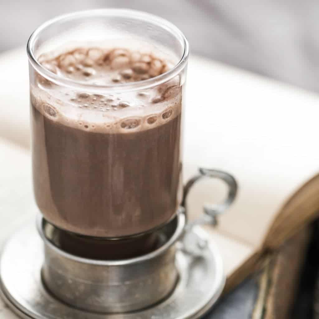 Bright photo of a coffee drink on a white book, which reflects light back on the glass. Example of how to take good photos for Instagram.