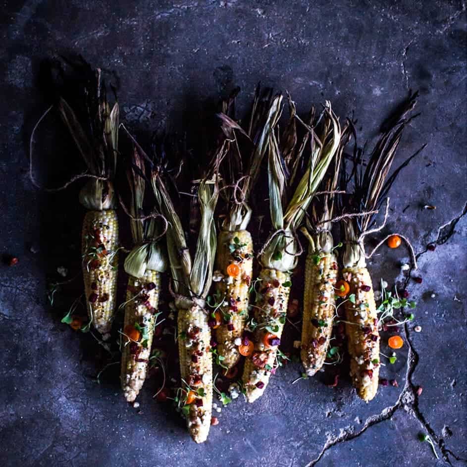 Grilled corn on the cob with vibrant spices on a moody concrete background