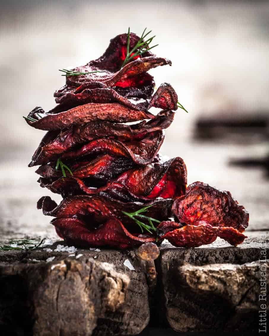 A stack of baked red beet chips with herbs. 