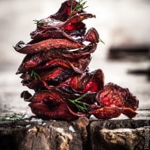 a stack of red beet chips on a wooden surfacce