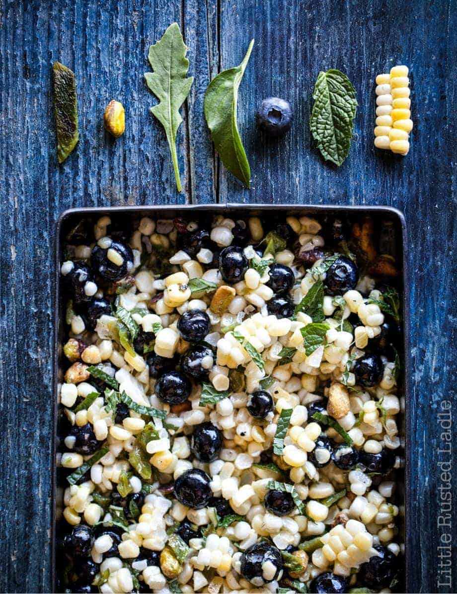 Flat lay of ingredients for blueberry sweet corn salsa above a finished dish of the salsa. 