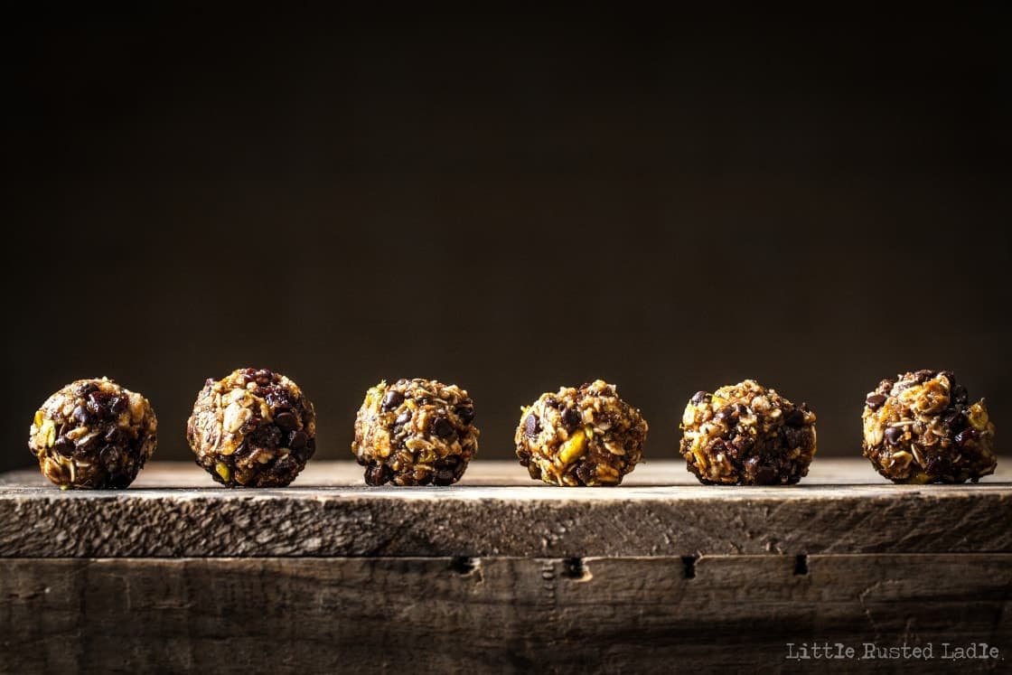 A line of textured healthy granola bites on a rustic wood surface. 