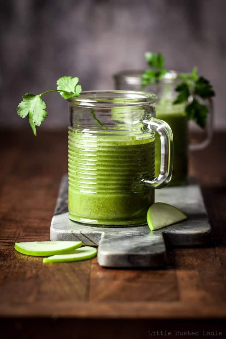 Glass jar with handle on marble cutting board filled with bright green healthy detox smoothie.