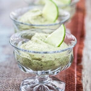 A receding line of crystal ice cream dishes filled with light green key lime pudding on rustic table runner.