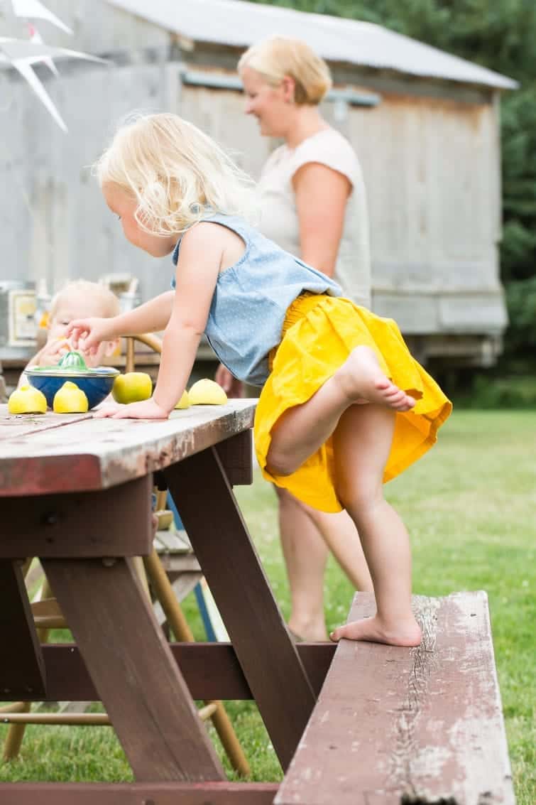 little girl on picnic table making lemonaid