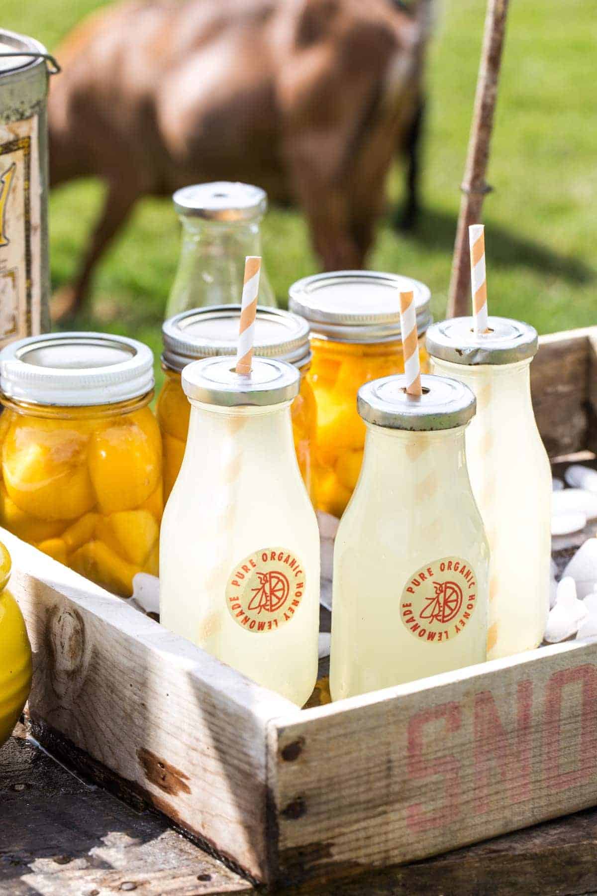 Honey Mint Peach Lemonade in glass bottles in a wooden tray