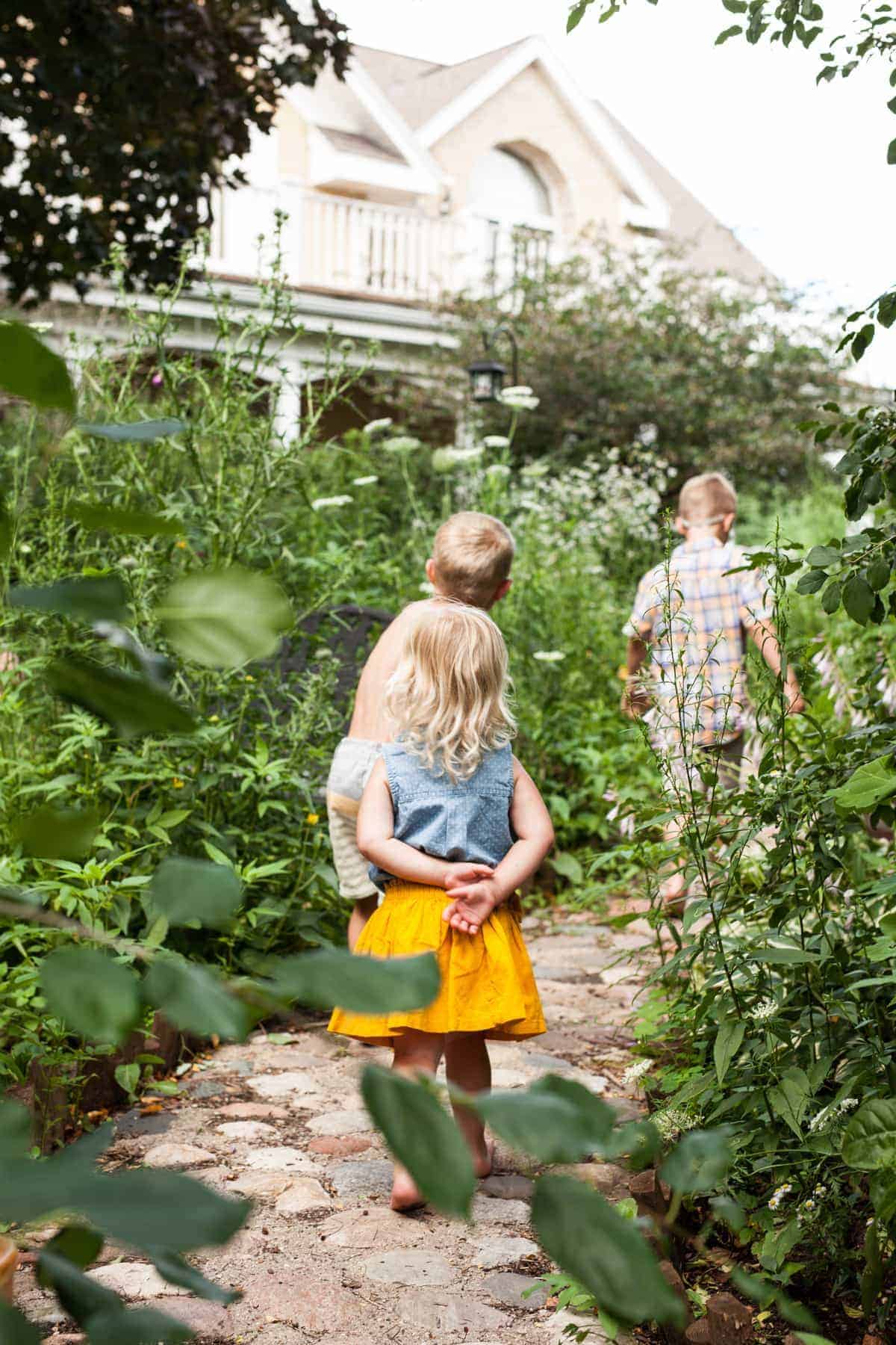 children walking up a stone path in a wild flower garden. 