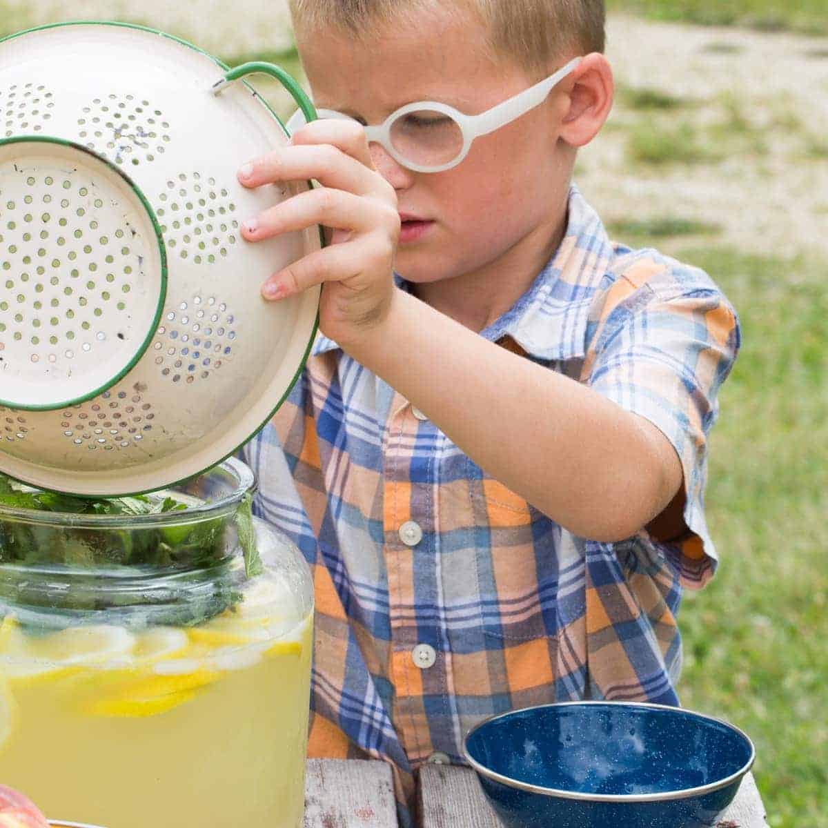 Boy with glasses pouring ingredients into the beverage container. 