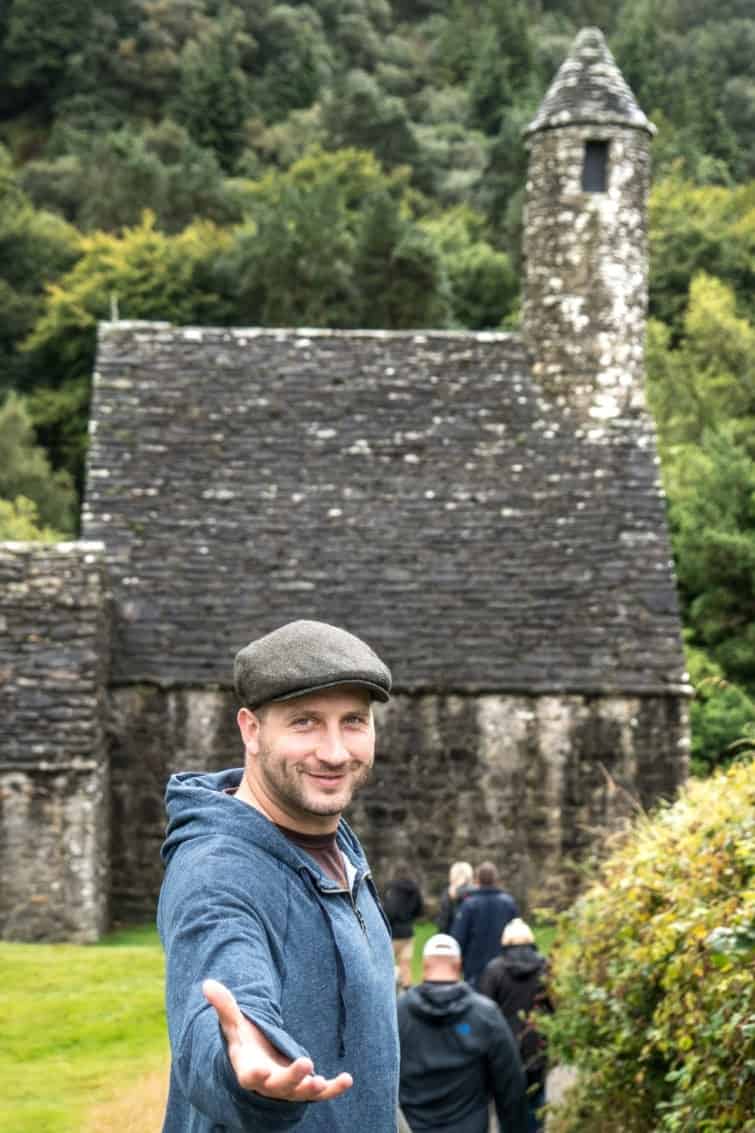 Man with his hand outstreached in from of an old church in Ireland