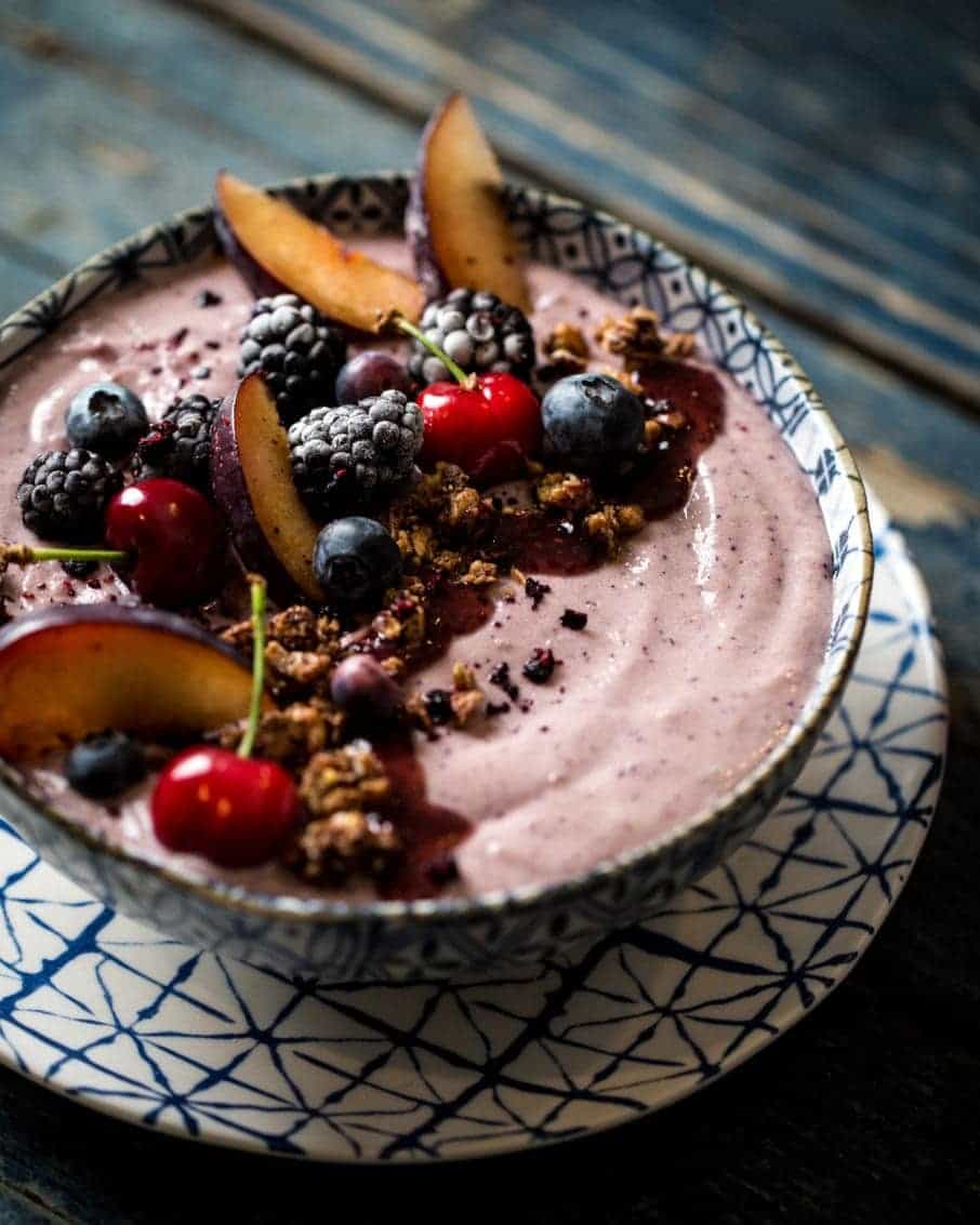 Bowl of smoothie with decorative fruit topping on a rustic surface