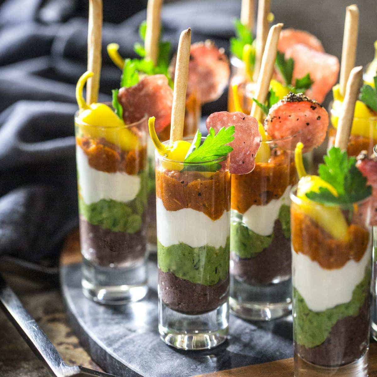 Layered Mediterranean Dip Shooters with Bread Sticks and Garnishes