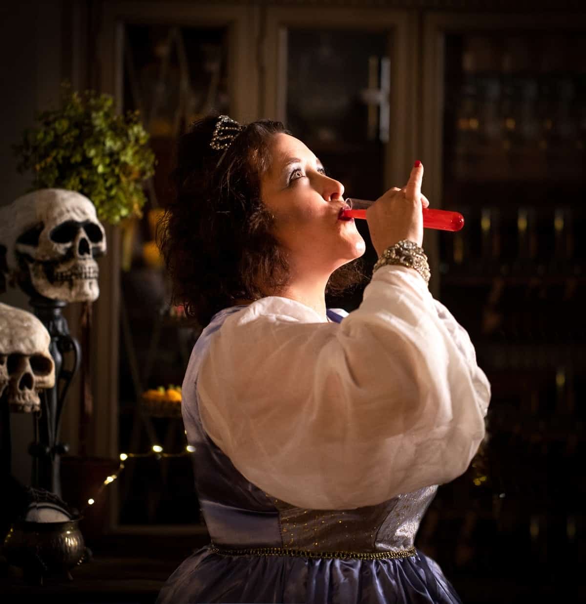 Woman dressed for Halloween as a princess taking a shot from the test tube