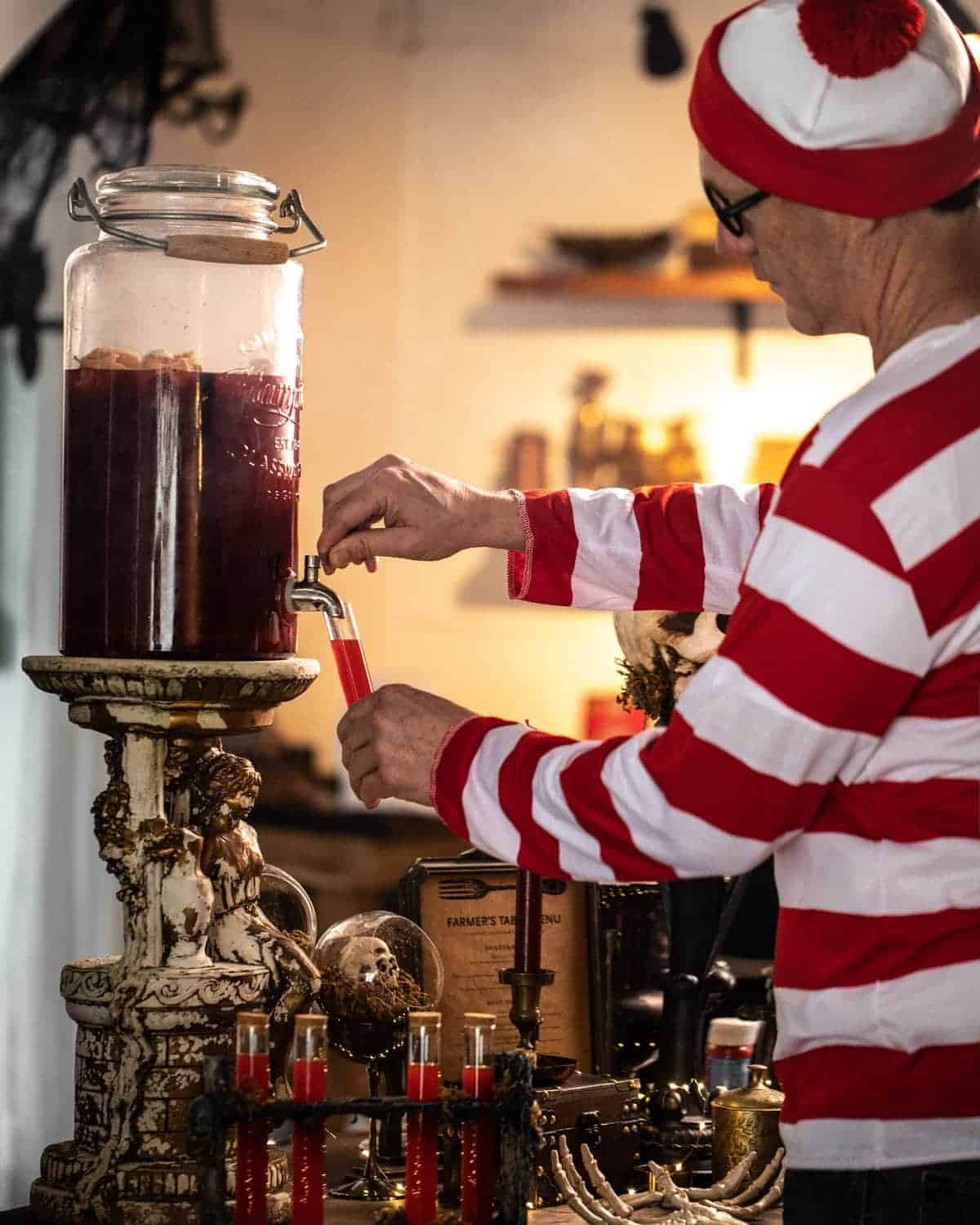 Man in Waldo costume filling his Halloween test tube. 