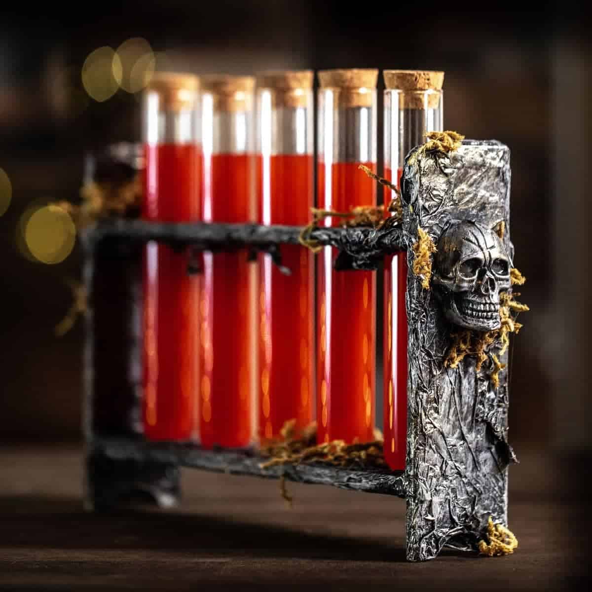 Black and silver test tube rack with skulls on the ends holding blood red halloween shots