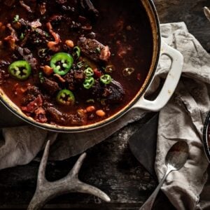 overhead shot of croc of venison chili with corn bread and antlers