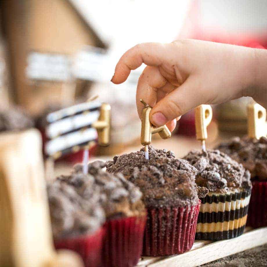 Child putting candles in coal cupcakes