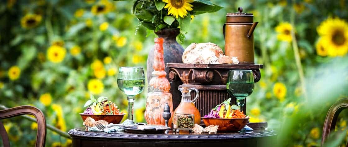 Wide image of an antique table spread with a sunflower field in the background. How to include a unique background for a good Instagram photo. 