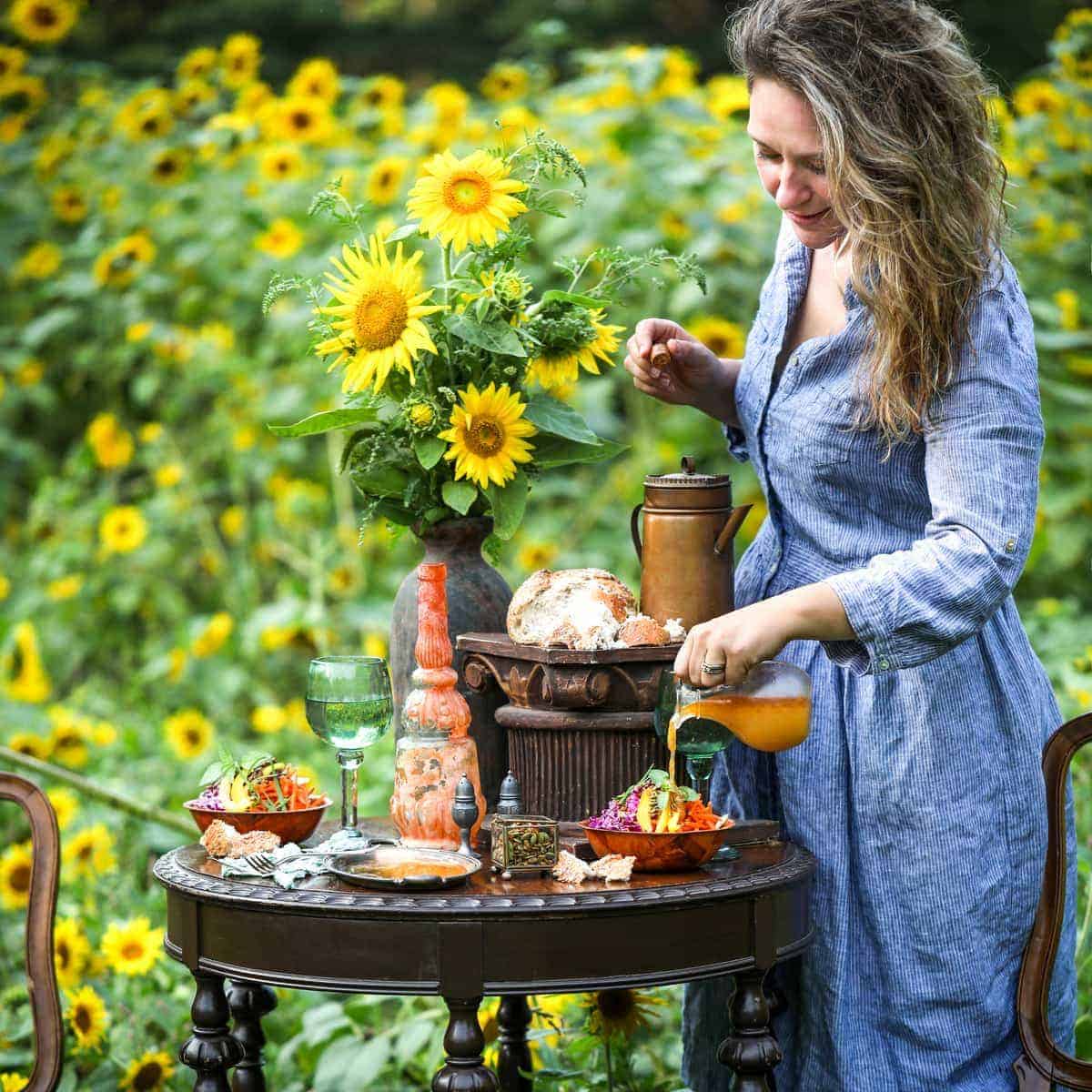 Jena Carlin standing by a table set up of sunflower dishes in a sunflower field