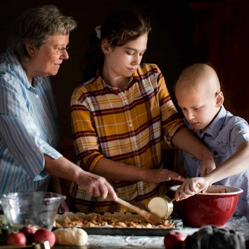 Grandmother and grandchildren working together to make an apple dessert