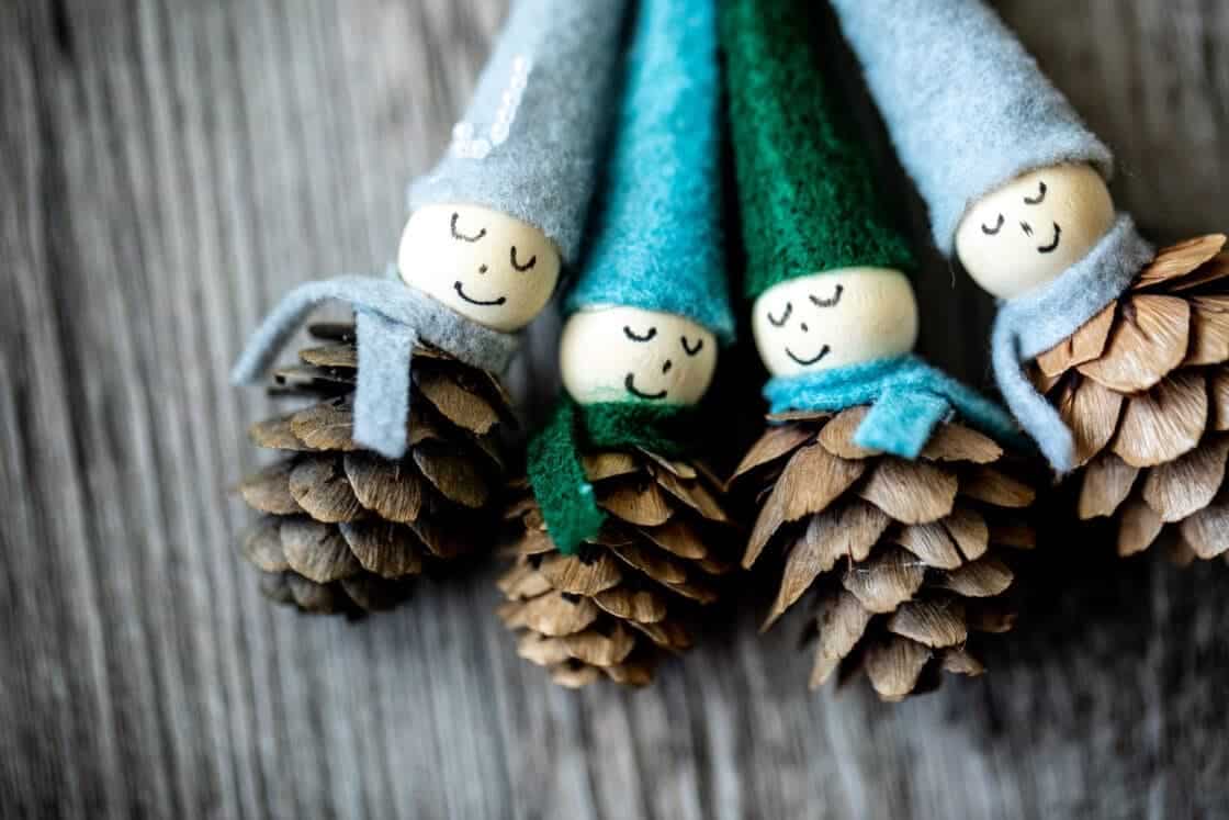 Four pine cone ornaments with blue, green, and gray felt hats and scarves. Secret Santa ideas. Handmade Gifts