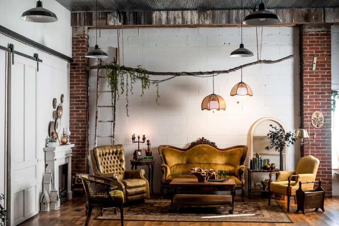 Wide angle image of a beautiful, rustic food photography studio sitting area for clients filled with antique furniture and props.