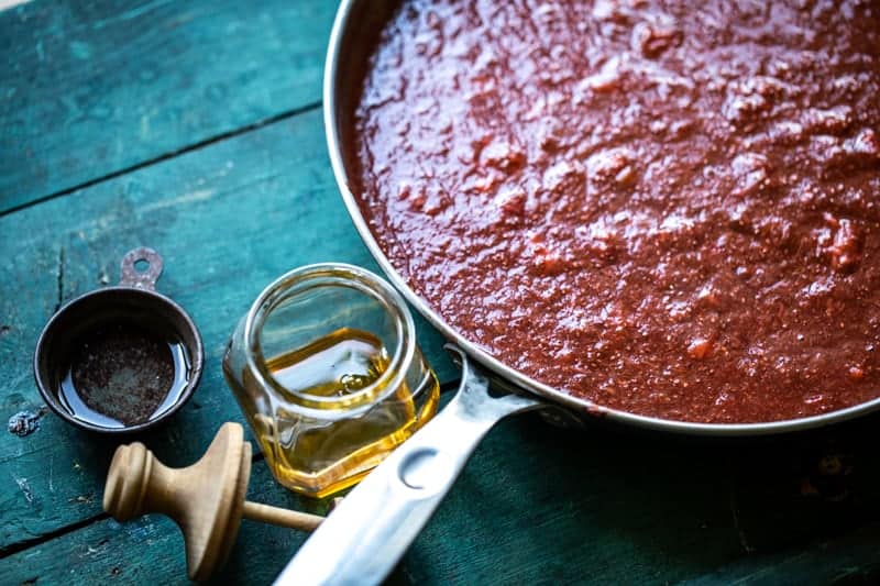 A saucepan with cooled jam with small containers of honey and vanilla. 