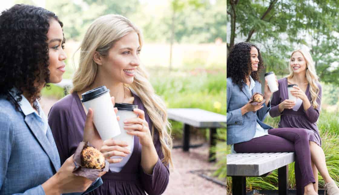 two women drinking coffee on a bench