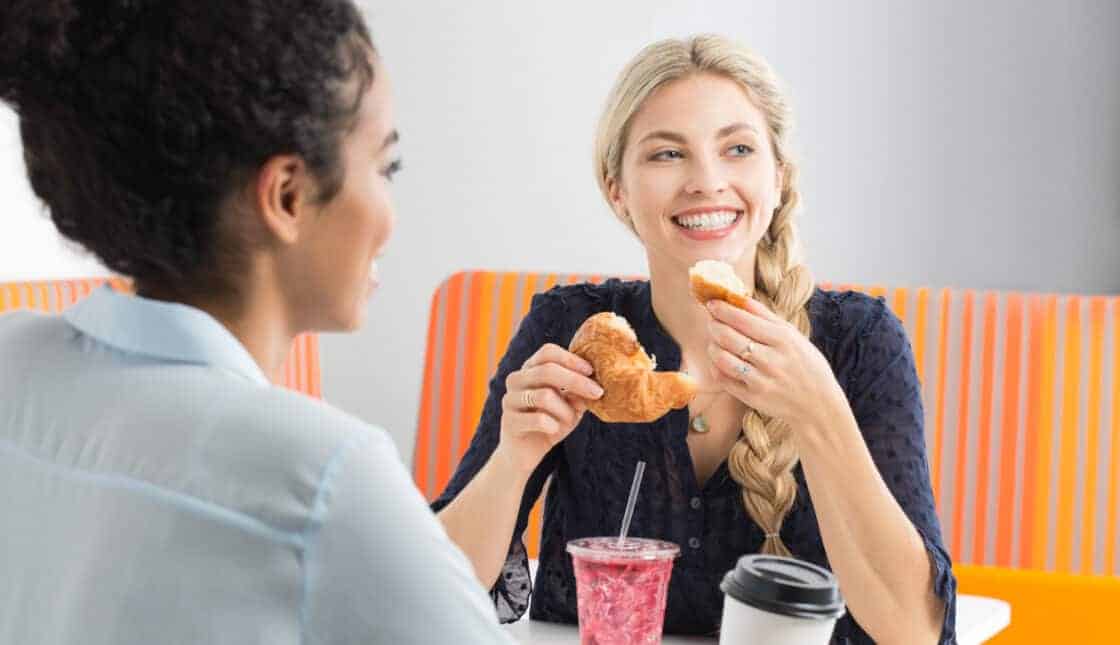 two people sitting in a colorful booth eating breakfast