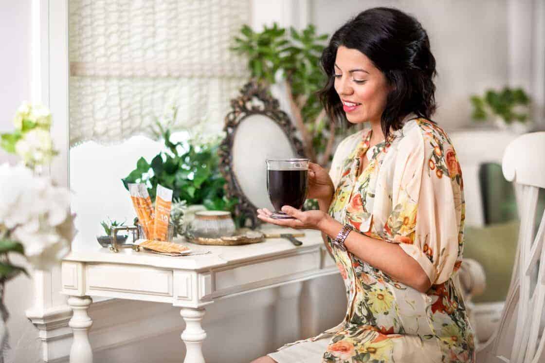 woman at a desk with a glass mug of coffee