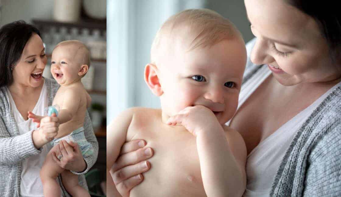 mother holding baby in a diaper by a window