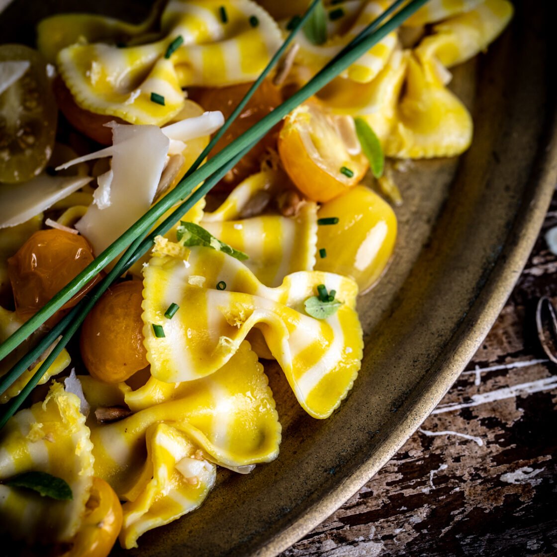 Close up of sunflower bowtie pasta dish on a vintage platter with fresh herbs. 