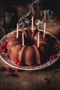 Chocolate bunt cake with blown out candles and swirling smoke.