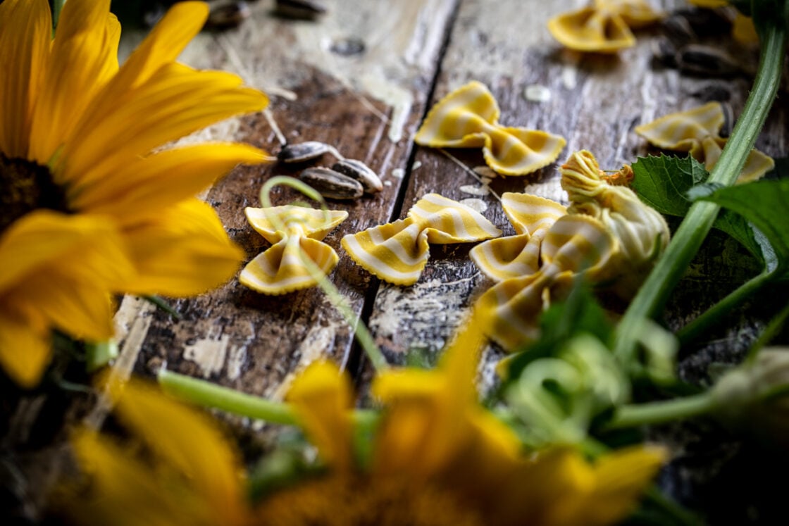 Sunflowers and striped pasta on a rustic wood food background with lots of layers of natural texture