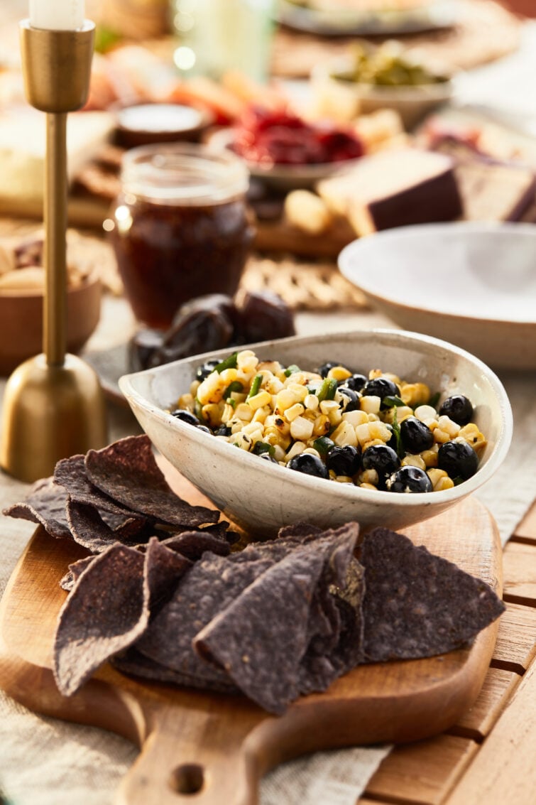 Bowl of corn blueberry salsa with lue corn chips in a bright outdoor setting